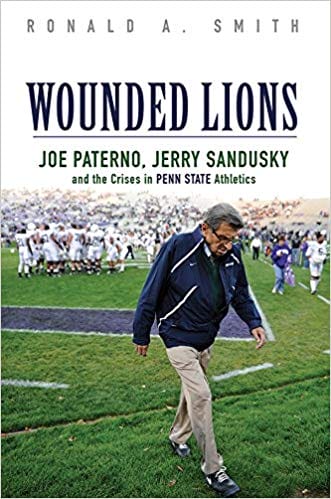 Book cover of "Wounded Lions" by Ronald A. Smith, featuring a football scene and a man walking on a field.