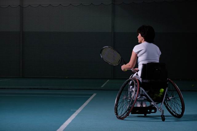 Wheelchair tennis player on indoor court preparing to hit a ball