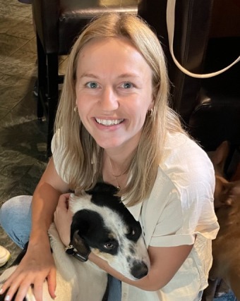 Woman smiling while hugging a black and white dog indoors.
